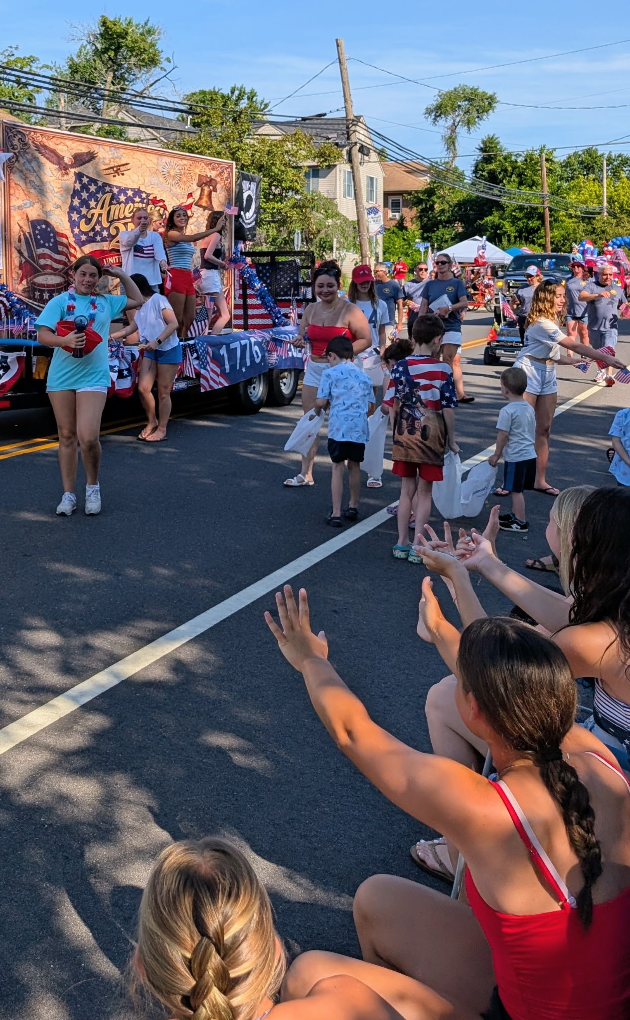Families lining the street wave to the America 250 float as kids run out to grab candy — Berlin NJ July 4th 2026 parade