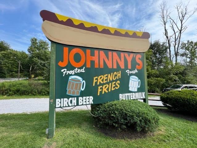 The hand-painted roadside sign &mdash; frosted birch beer, fresh buttermilk. The signature pairing Hot Dog Johnny&rsquo;s never modernized away.