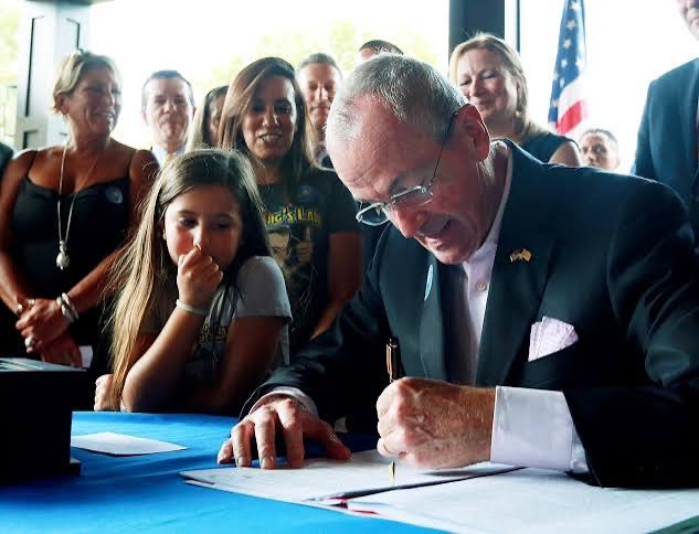 Governor Phil Murphy signs cannabis legalization legislation surrounded by supporters
