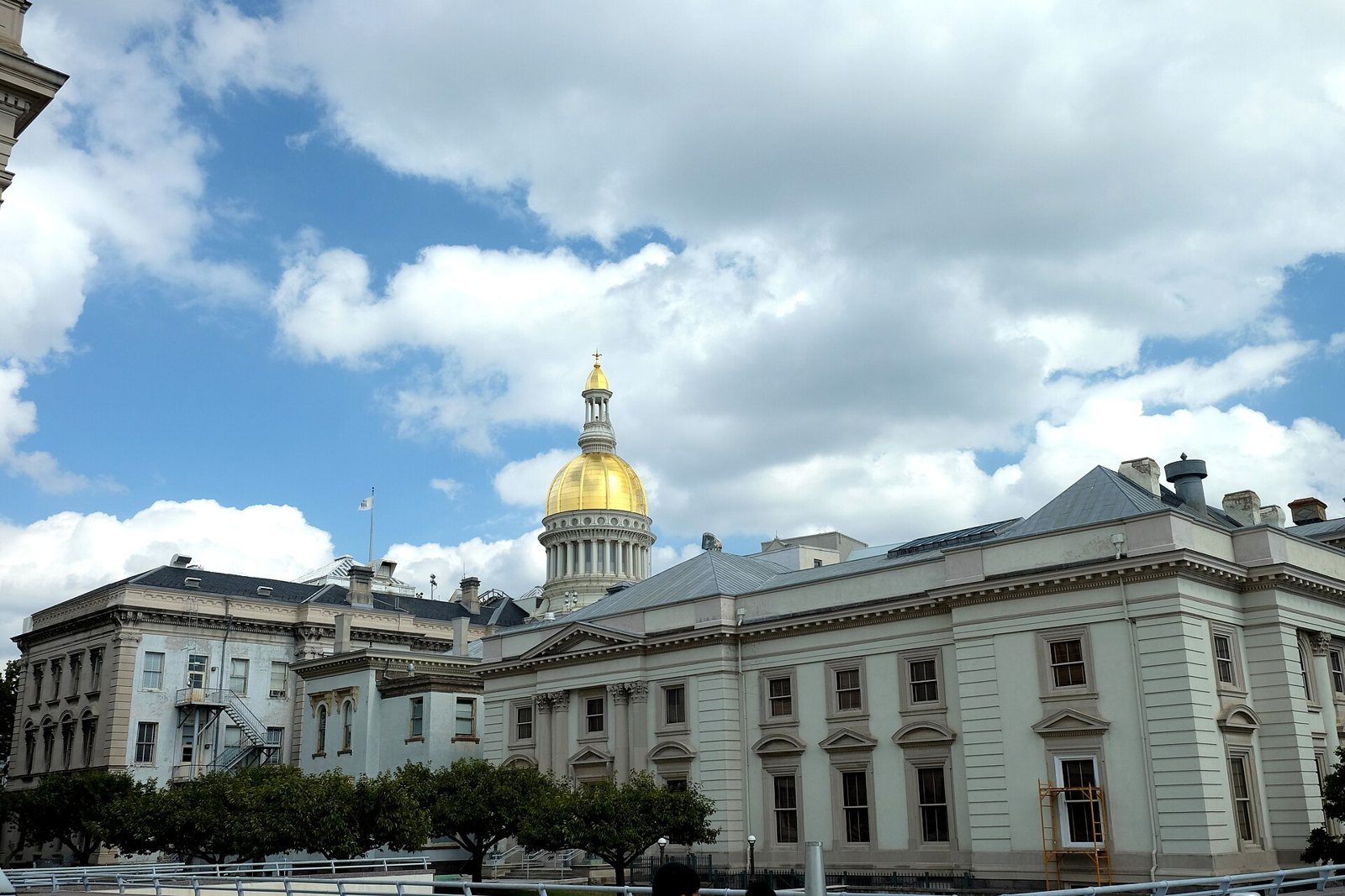 The gold dome of the New Jersey State House rising behind state office wings in Trenton